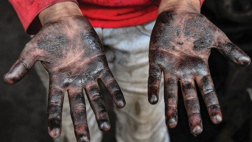 A young Syrian boy working at a machine repair shop, shows his oil-stained hands, in the town of ...