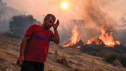 TOPSHOT - A man rubs his eyes as a fire burns into the village of Gennadi on the Greek Aegean island ...