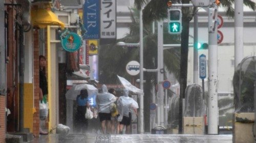 epa10781066 People walk along Kokusai-dori under strong wind and rain by Typhoon Khanun in Naha, ...