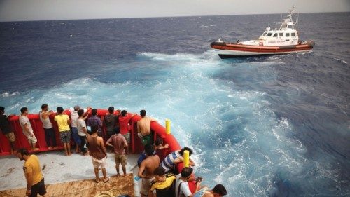 FILE PHOTO: Migrants on board of NGO Proactiva Open Arms Uno rescue boat looks at boat Guardia ...