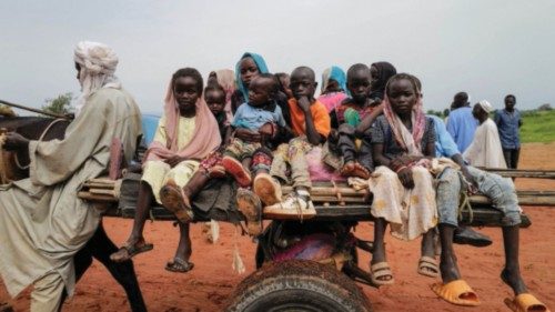 Sudanese children, who fled the conflict in Murnei in Sudan's Darfur region, ride a cart while ...