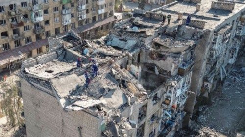 Rescuers work with heavy machinery, at the site of a building destroyed during a Russian missile ...