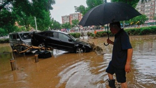 (FILES) A man wades past a damaged car along a flooded street, after heavy rains in Mentougou ... (FILES) A man wades past a damaged car along a flooded street, after heavy rains in Mentougou ...