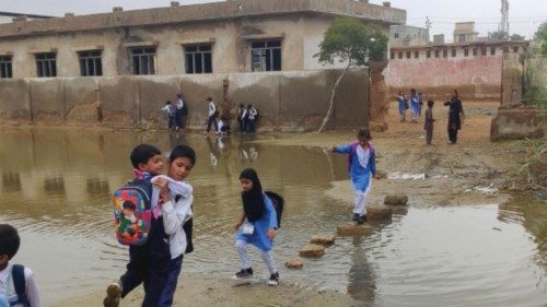 epa10783098 Pakistani school children make their way home through a flooded area after monsoon rains ...