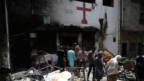 Police officials and residents stand amid debris outside the torched Saint John Church in Jaranwala ...