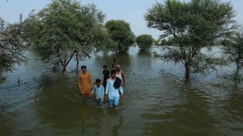 People wade through a flooded area of the town of Burewala, in the Vehari district in Punjab ...
