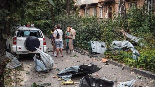 Local residents stand near their apartment building damaged during a Russian missile strike, amid ...