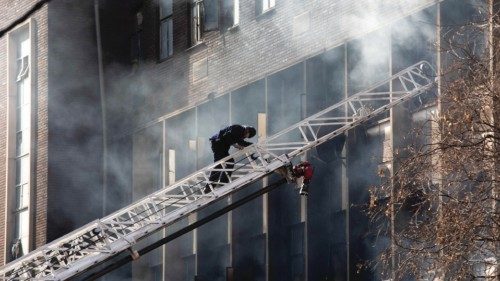 epa10830426 An emergency services member climbs a ladder at the site of a fire that broke out at a ...