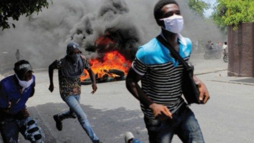 FILE PHOTO: Men run next to burning tires during a protest demanding an end to gang violence, in ...