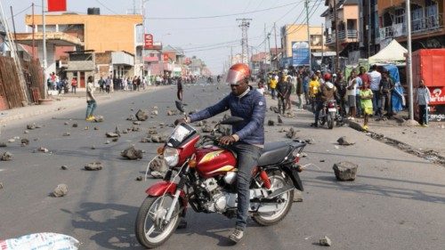 A Congolese rider navigates past rocks mounted as barricades along the road during a demonstration ...