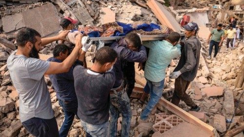 People carry the remains of a victim of the deadly 6.8-magnitude September 8 earthquake, in the ...