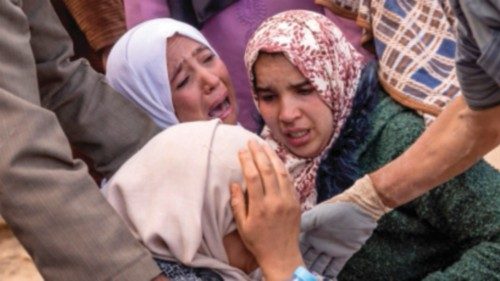 Women react as volunteers recover the body of a familly member from the rubble of collapsed houses ...