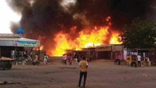 TOPSHOT - A man stands by as a fire rages in a livestock market area in al-Fasher, the capital of ...
