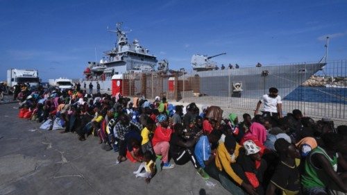 Hundreds of migrants wait in line at the port pier to be boarded on the military ship Cassiopea and ...