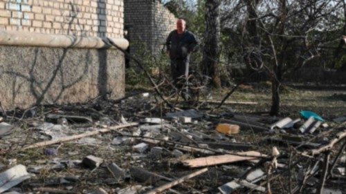 A man stands next to debris following the recent Russian shelling in an urban-type settlement of ...
