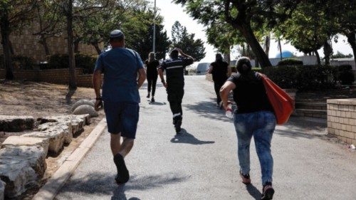 People run for shelter while sirens sound as rockets from Gaza are launched towards Israel, in ...