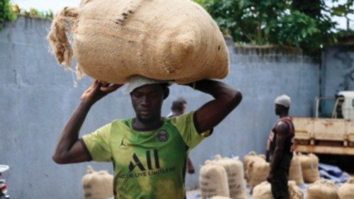 epa10917596 A farmer carries a sack with cocoa beans in a warehouse in the town of Adzope town, ...