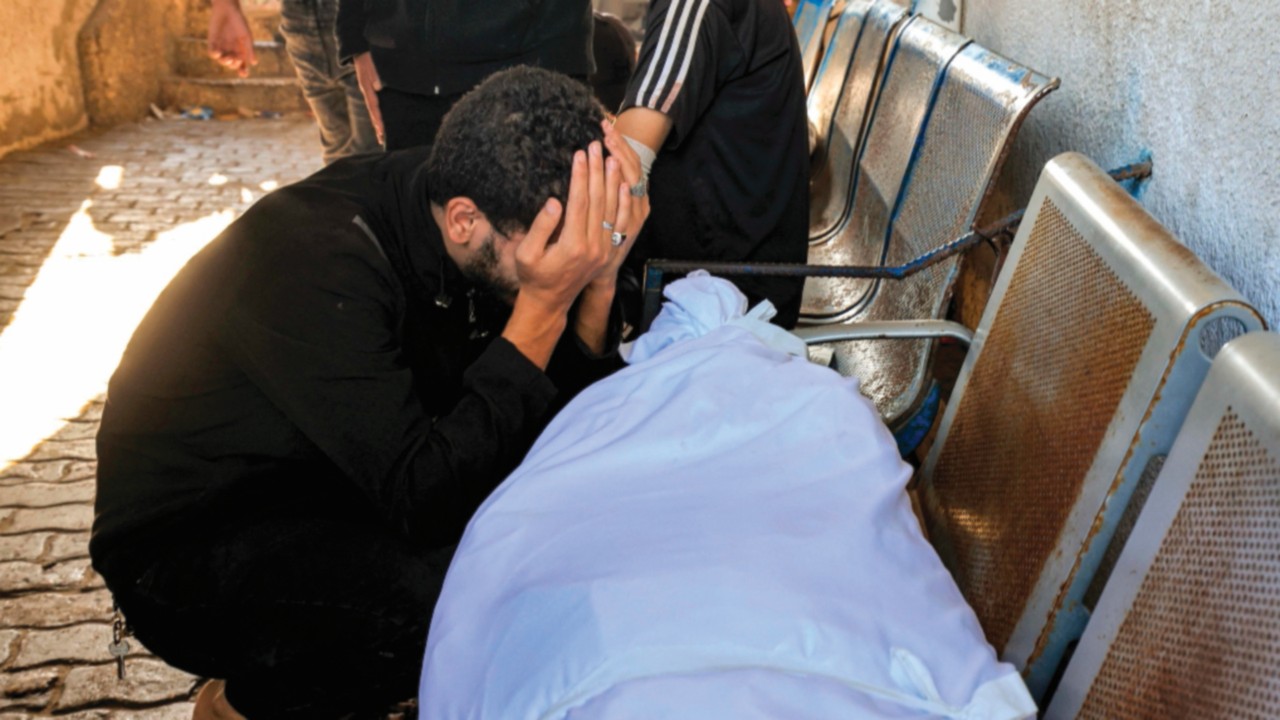 EDITORS NOTE: Graphic content / A man reacts by one of the wrapped bodies of victims who died in an ...