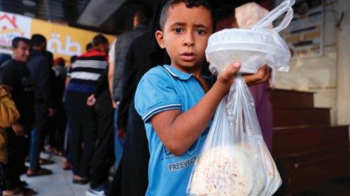 A boy returns home with bags of food in Rafah in the southern Gaza Strip on October 20, 2023, amid ...