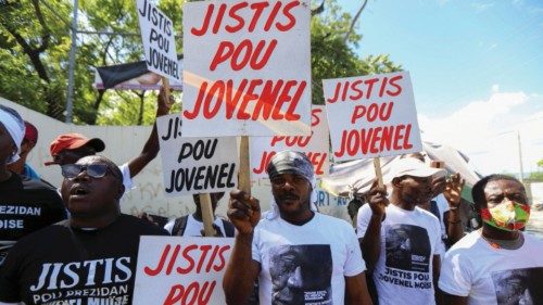 FILE PHOTO: Demonstrators hold signs reading 'Justice for Jovenel' outside a judicial hearing into ...