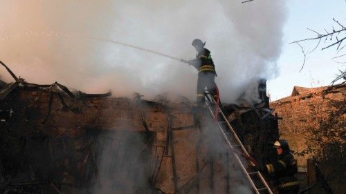 Firefighters battle a fire in a house hit by shelling, that killed a man and injured a woman, in ...