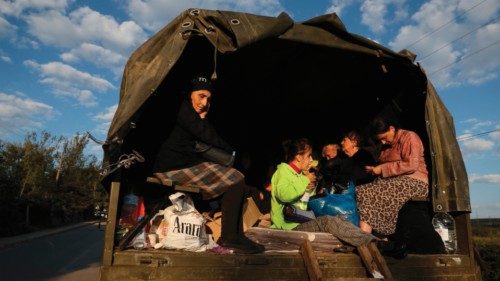 Refugees sit on the back of a truck with loaded belongings near Kornidzor on September 28, 2023. ...