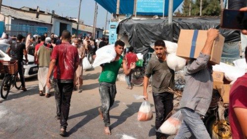 Palestinians collect boxes and and bags from a UN-run aid supply center, distributing food to local ...