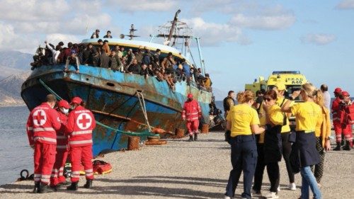 FILE PHOTO: Red Cross volunteers and rescue crews stand next to a fishing boat carrying migrants at ...