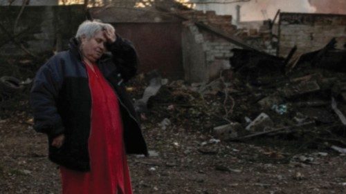 A local resident reacts while standing in a courtyard near damaged buildings hit by recent shelling ...