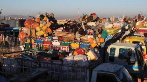 Afghan nationals with belongings sit atop a truck as they head back with their families to ...