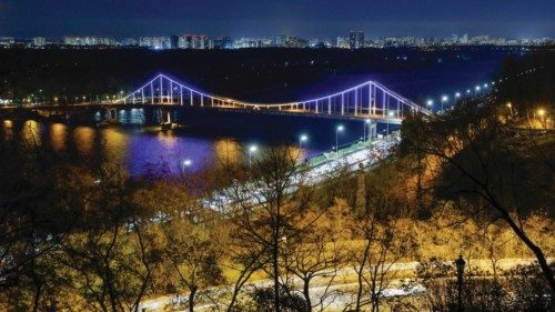 epa10968929 The Parkovyi footbridge spanning over Dnieper river is illuminated in the evening in ...