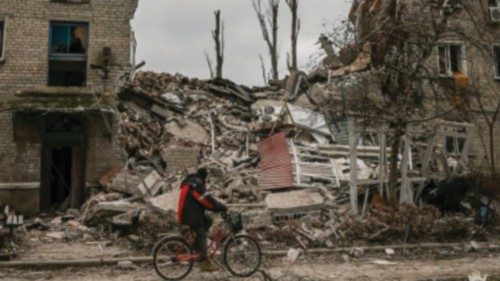 EDITORS NOTE: Graphic content / (FILES) A man rides his bicycle in front of a destroyed apartment ... EDITORS NOTE: Graphic content / (FILES) A man rides his bicycle in front of a destroyed apartment ...
