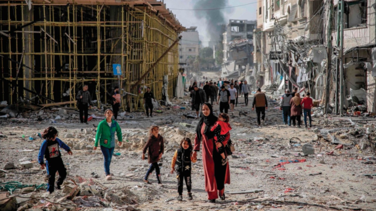 TOPSHOT - Palestinians walk amid the rubble of destroyed buildings in Gaza City on the northern Gaza ...