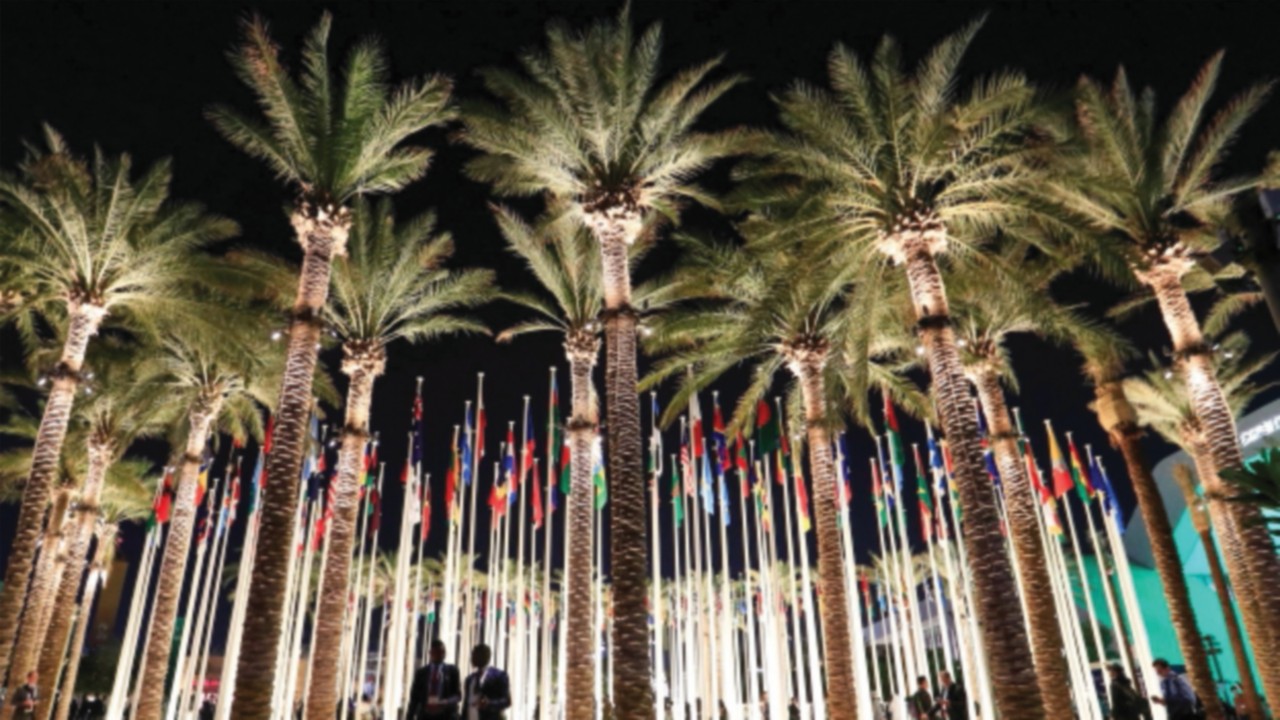 Delegates walk past flag posts at the Dubai's Expo City after attending the World Climate Action ...