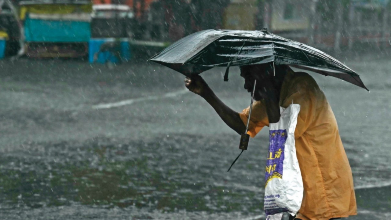 A pedestrian wades through a flooded street after heavy rains in Chennai on December 4, 2023. ...