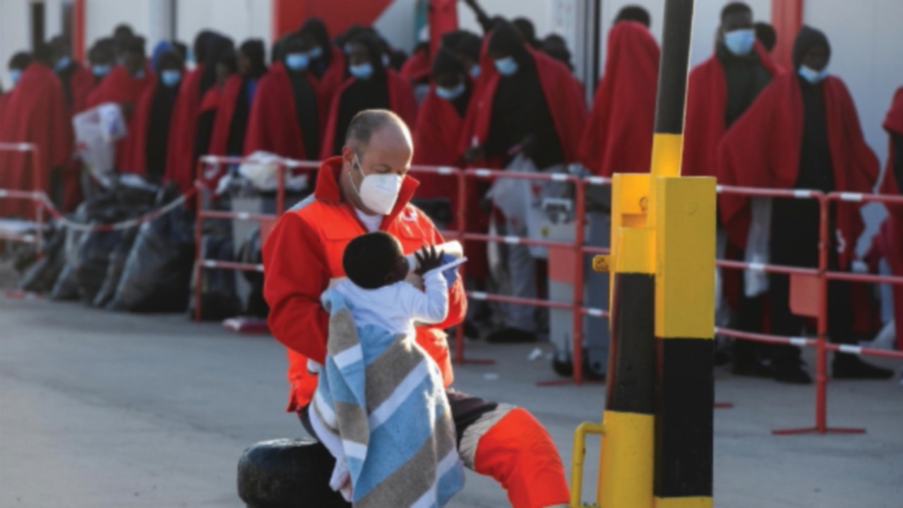 epa11000754 A Red Cross member feeds a baby with a bottle at Gran Tarajal port after the arrival of ...