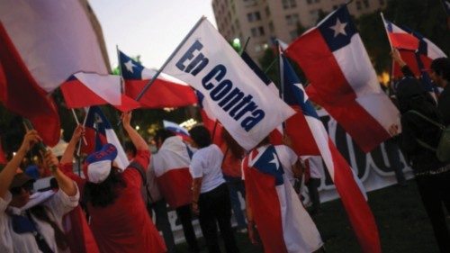 A person holds a flag that reads 'Against' while others hold Chilean national flags, on the day of ... A person holds a flag that reads 'Against' while others hold Chilean national flags, on the day of ...