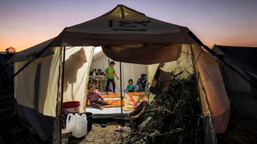 Firewood is placed at the entrance of a tent where children are sitting, at a camp housing ... Firewood is placed at the entrance of a tent where children are sitting, at a camp housing ...