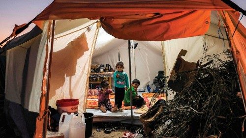 Firewood is placed at the entrance of a tent where children are sitting, at a camp housing ... Firewood is placed at the entrance of a tent where children are sitting, at a camp housing ...