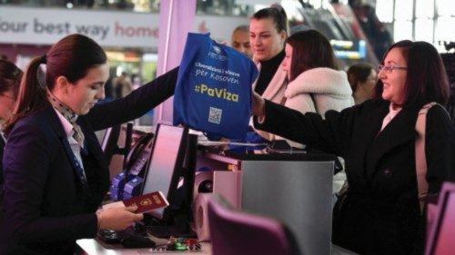 An airline staff member gives a passenger a tote bag with a sign that reads '#WithoutVisa' as Kosovo ... An airline staff member gives a passenger a tote bag with a sign that reads '#WithoutVisa' as Kosovo ...
