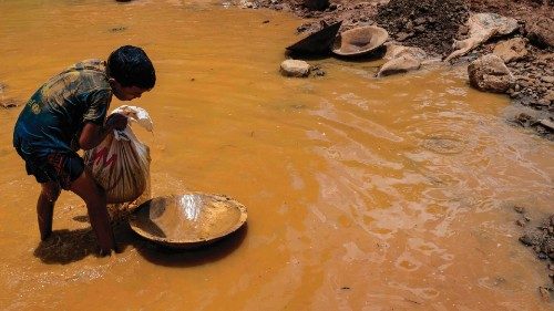 A Venezuelan mining boy unloads a bag of mud into a wooden container used to strain and wash mud in ...
