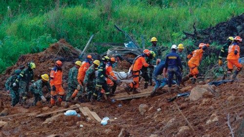 TOPSHOT - Members of the rescue team carry a corpse found in the area of a landslide in the road ...