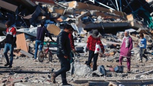 People pass by a collapsed building the Al-Maghazi refugee camp in central Gaza Strip, on January ... People pass by a collapsed building the Al-Maghazi refugee camp in central Gaza Strip, on January ...