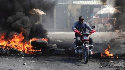 A motorcyclist reacts while driving through a burning barricade, one of many across several ...