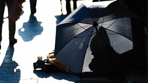 A beggar woman protects herself from the cold and wind behind an umbrella in a street of Milan on ... A beggar woman protects herself from the cold and wind behind an umbrella in a street of Milan on ...