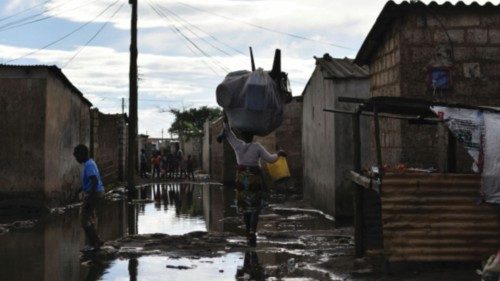 People walk across a flooded street in a neighbourhood affected by the cholera outbreak in Lusaka, ...
