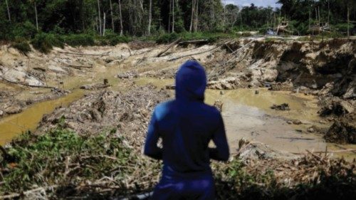 An illegal miner looks at a destroyed forest area, while being detained by a members of the Special ...