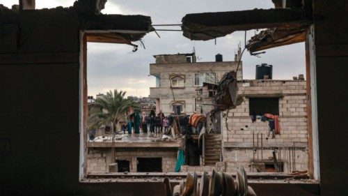 A picture taken through the window of a building damaged by Israeli bombing, shows members of a ... A picture taken through the window of a building damaged by Israeli bombing, shows members of a ...