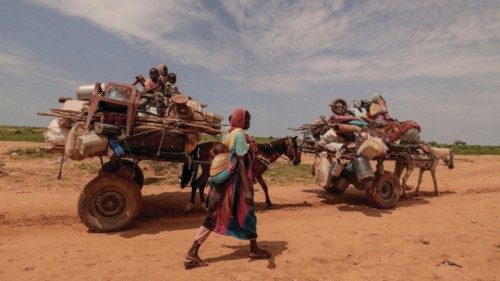 FILE PHOTO: A Sudanese woman, who fled the conflict in Murnei in Sudan's Darfur region, walks beside ...