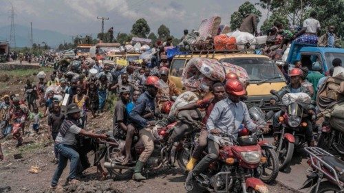 TOPSHOT - People gather at a busy road while carrying some of their belongings as they flee the ... TOPSHOT - People gather at a busy road while carrying some of their belongings as they flee the ...